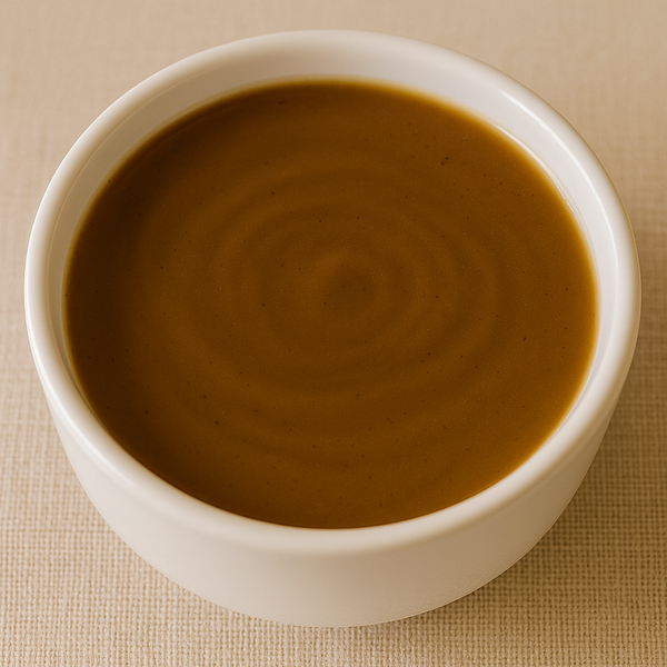 White bowl filled with brown gravy on a beige background